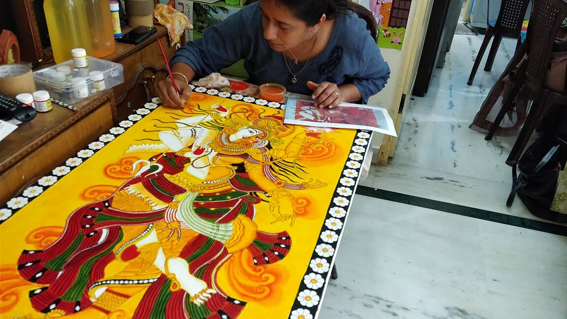Student painting a tall Kerala Mural figure